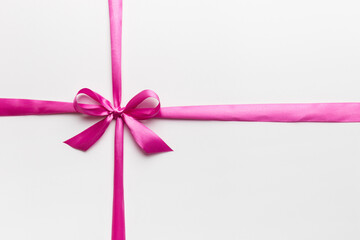 Top view of purple ribbon rolled and pink bow isolated on colored background. Flat lay with copy space