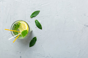 Caipirinha, Mojito cocktail, vodka or soda drink with lime, mint and straw on table background. Refreshing beverage with mint and lime in glass top view flat lay