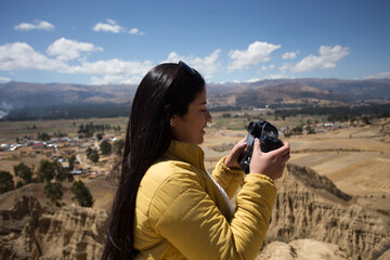 Mujer turista tomando fotos con una cámara profesional en una montaña turística de sudamérica. Concepto de tecnología, viajes, vacaciones y turismo. - obrazy, fototapety, plakaty