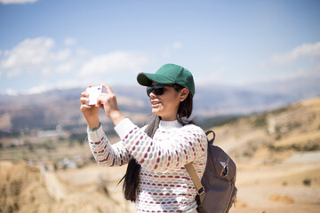 Mujer joven tomando fotos con su teléfono en un lugar turistico. Concepto de viajes, vacaciones y...