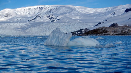 Icebergs floating at the base of snow covered mountains in Cierva Cove, Antarctica