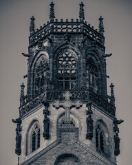 Vertical monochrome of the gothic church tower with a big cross