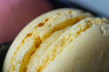 Close-up of flavourful yellow macaron on blurry background. Sweet concept. Excellent image for dessert banners and advertisements. 