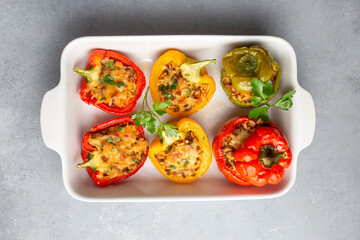 Stuffed peppers, halves of peppers stuffed with rice, dried tomatoes, herbs and cheese in a baking...