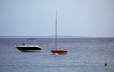 A boat and a yacht on a rough sea on a cloudy and gloomy day