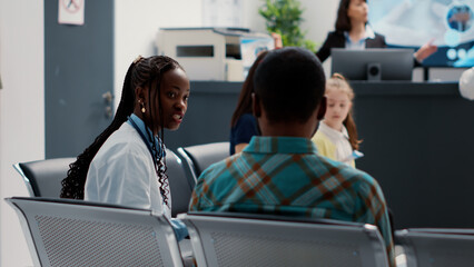 African american physician and patient talking about diagnosis results on medical report files, sitting in hospital waiting area. People doing healthcare consultation in clinic lobby. Close up.