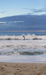 surfer in ocean waves at sunset 