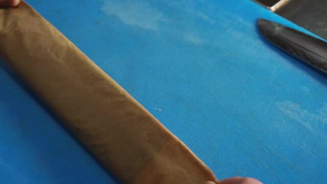 Chef rolling up white cod fish for baking in a Parchment Pape renvelope
