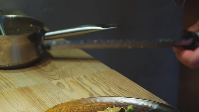 Chef grating lemon zest on grater on a cooked dish of baked fish