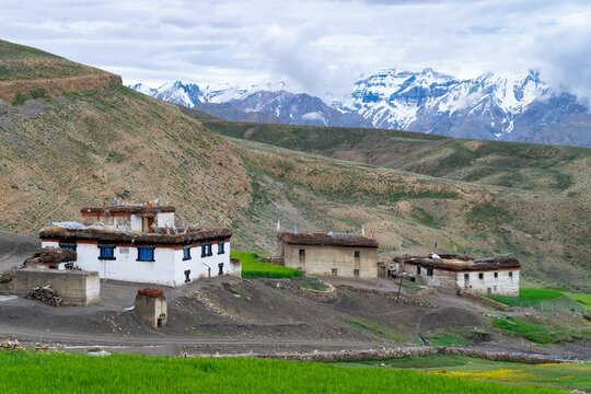 Out houses in Hikkim village, India in the middle of mountains with low clouds in the background