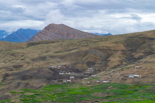 Out houses in Hikkim village, India in the middle of mountains with low clouds in the background