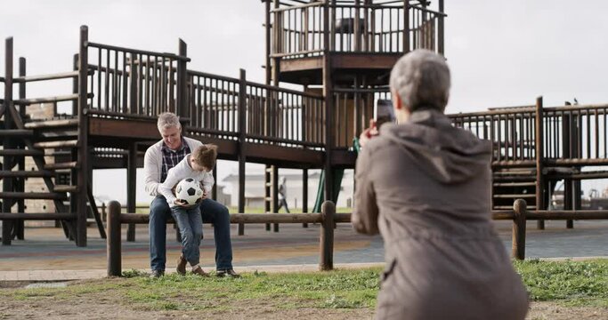 Photo taken of excited grandfather and happy boy bonding with a soccer ball at a fun outdoors playing park. Smiling family together in nature being active. Senior male and child posing for a picture