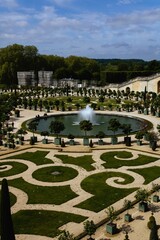 A part of the garden of Versailles with a fountain and well design pattern of grass