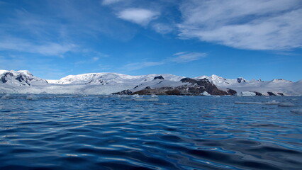 Icebergs floating at the base of snow covered mountains in Cierva Cove, Antarctica