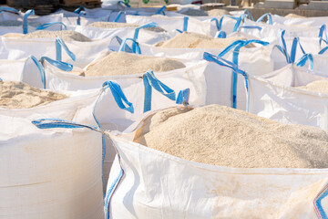 Image of bags with primer standing in a warehouse of building materials. Close-up image