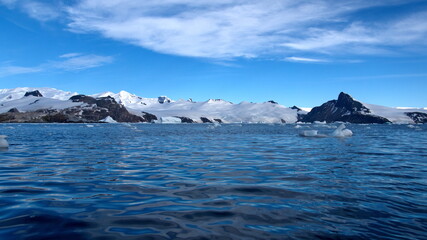Icebergs floating at the base of snow covered mountains in Cierva Cove, Antarctica