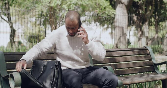 Distracted businessman dropping laptop while on a phone call, checking for damage while working in the park. Male entrepreneur making conversation and having an accident with pc