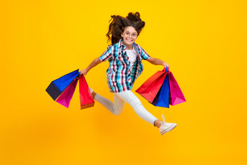 Amazed teen girl. Girl teenager with shopping bags isolated on yellow backgound. Shopping and sale concept. Excited expression, cheerful and glad.