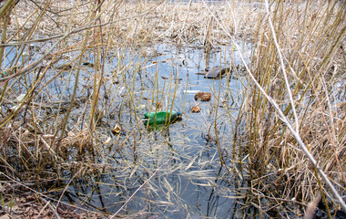 Garbage lies in the water on one of the urban landscape. plastic bottles were thrown into the water. Garbage in the water. Environmental plastic pollution. Ecological catastrophe of planet Earth.