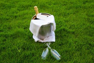 In einem Sektkühler steckt eine Champanger Flasche und zwei Gläser liegen davor.
 - obrazy, fototapety, plakaty