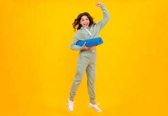 Fototapeta na wymiar Teen girl dressed in sports uniform. Teenager in a posh stylish sports suit in a hoodie with a hood hold yoga mat. Advertising sportswear tracksuit. Healthy kids lifestyle, sport.