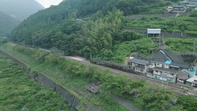 Short train arrives at outdoor station in small mountain village 