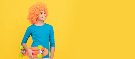 happy teen girl in fancy clown wig hold penny board, childhood. Funny teenager child in wig, party poster. Banner header, copy space.