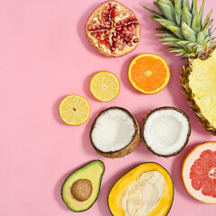 Ripe organic half sliced tropic fruits on pastel pink background. Flat lay. Summer cncept