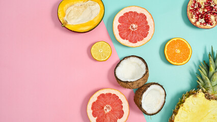 Ripe organic half sliced tropic fruits on pastel pink and cyan background. Flat lay. Copy space. Summer cncept