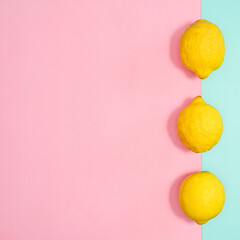 Summer background with ripe lemons with copy space on pastel pink and cyan background. Flat lay. MInimal tropical concept