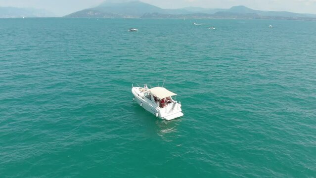 Beautiful HD drone footage of a white boat siling in the Lake Garda on a sunny day in Italy