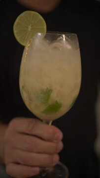 Vertical view of a man handing the drink caipirinha