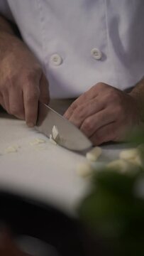 Vertical view of a man preparing a pizza with a garlic in the kitchen