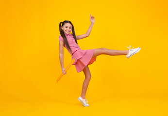 Fototapeta na wymiar Measuring school equipment. Schoolgirl holding measure for geometry lesson, isolated on yellow background. Student study math. Crazy jump, jumping kids.