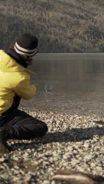 Vertical back view of male throwing rock on the water