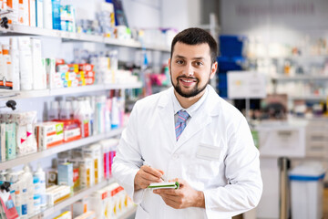 Fototapeta na wymiar Male pharmacist checking assortment of drugs in pharmacy