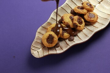Closeup of tasty chocolate cookies with drizling melting chocolate on a leaf-shaped plate
