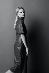 Fashion cool offer. Beautiful confident young woman looks over her shoulder at camera posing at studio background. Black and White concept. Art fashion photoshoot