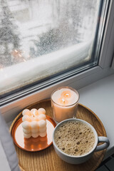 Cozy atmosphere winter still life with hot drink and candles on the windowsill