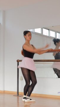 vertical video of a young ballet dancer performing ballet exercises in a dance studio