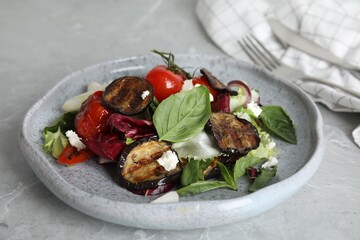 Delicious salad with roasted eggplant, basil and cheese served on grey marble table