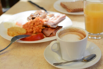 Cup of coffee and delicious breakfast served on beige table