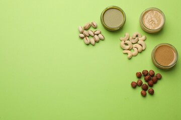 Fototapeta na wymiar Different types of delicious nut butters and ingredients on light green background, flat lay. Space for text