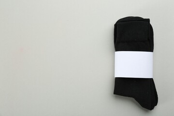 Pair of black cotton socks on grey background, top view. Space for text