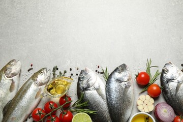Flat lay composition with dorada and cutthroat fish on light grey table, space for text