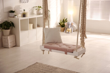 Beautiful swing with pillow in room. Stylish interior design