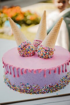 Pink And Purple Drip Cake With Waffle Cones With Sprinkles On It - Vertical Shot