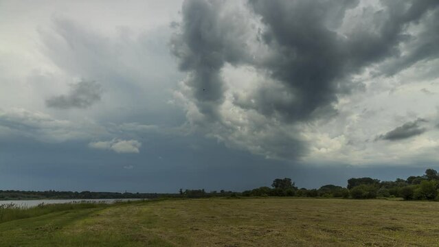 Timelapse of the dramatic clouds passing the meadow and the river