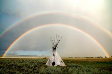 White conical tent resembling a tipi against the rainbow background - obrazy, fototapety, plakaty