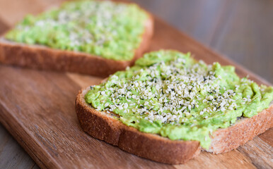 Side view simple avocado toast with hemp hearts on wood board